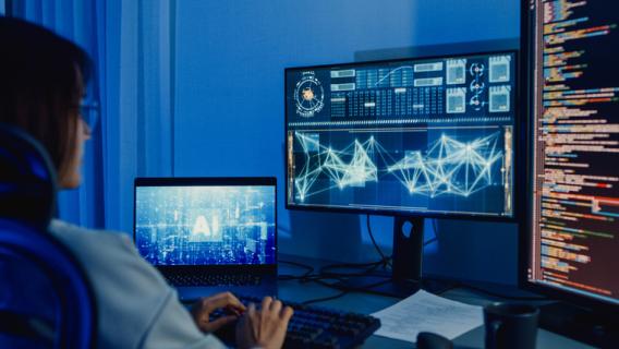 Une femme devant des ordinateurs mentionnant l'usage de l'intelligence artificielle