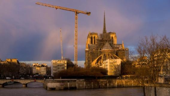 vue de la cathédrale notre dame de paris en chantier, avec une grue et des échafaudages