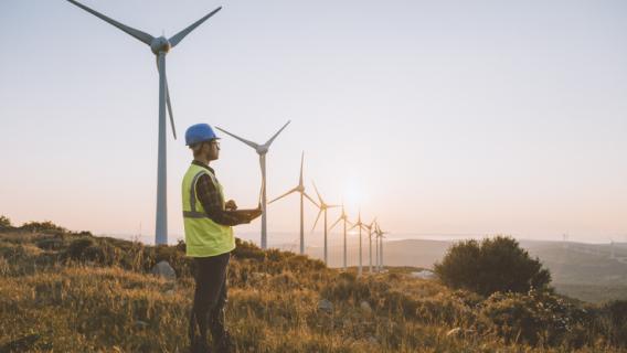 Un homme qui travaille, posté devant des éoliennes