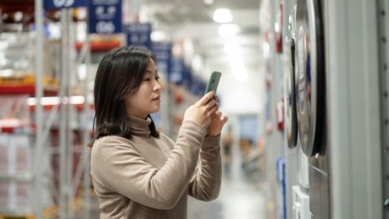 une femme scanne une étiquette sur un produit électroménager dans un magasin