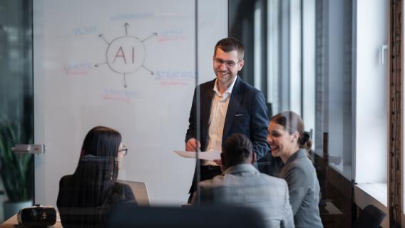 groupe de travail composé d'hommes et de femmes devant un tableau de présentation manuscrit en lien avec l'IA