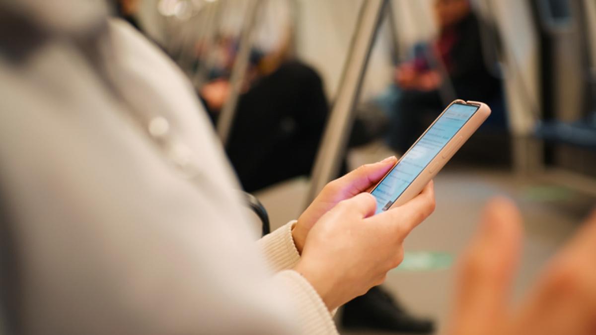 Femme dans le métro tenant un smartphone dans ses mains