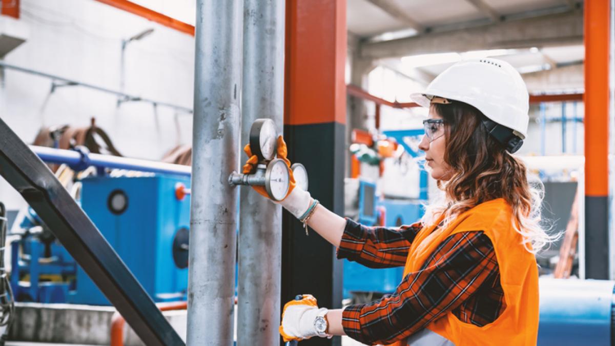femme équipée d'un casque travaillant dans une usine