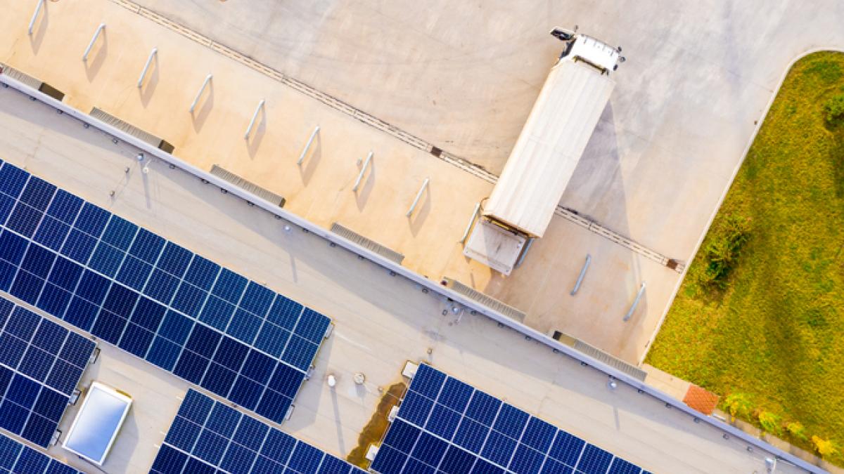 batiment vue d'en haut avec panneaux solaires sur le toit. Un camion est garé dos à un ponton de chargement