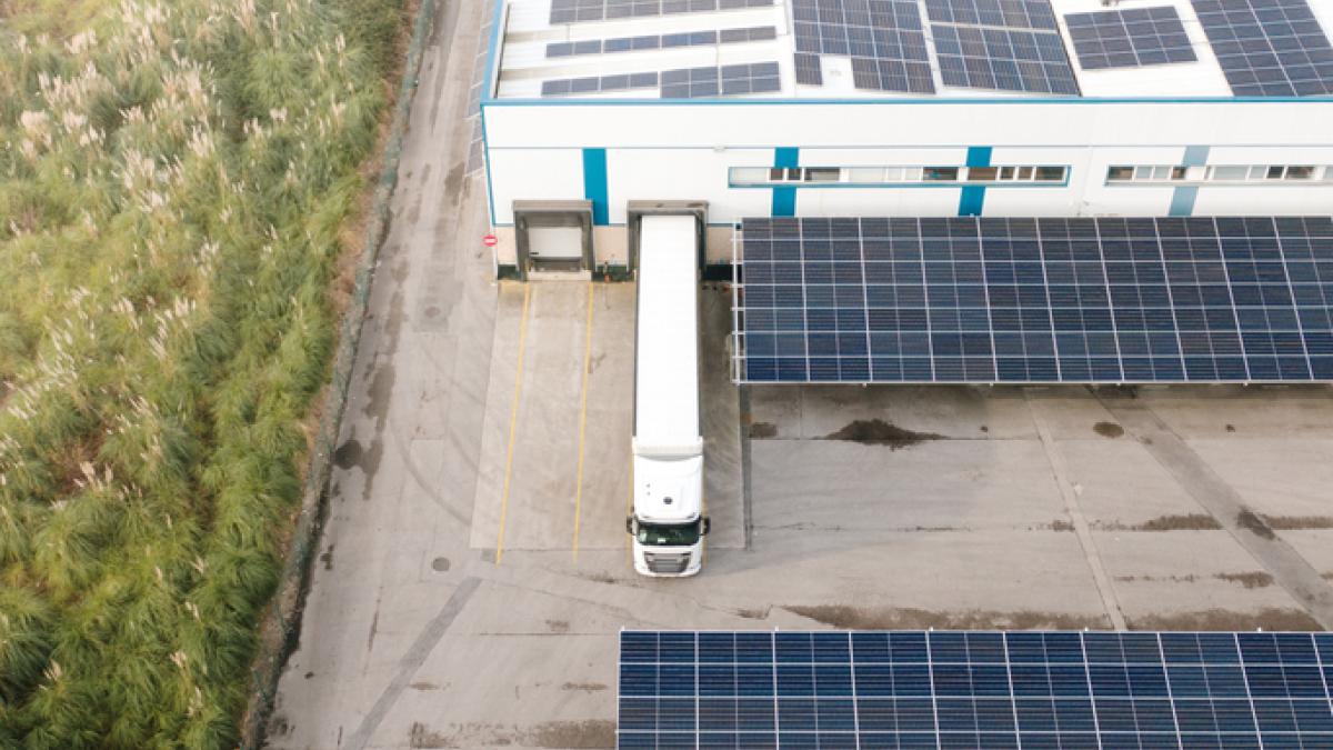 camion électrique sortant d'un bâtiment d'entreprise recouvert de panneaux solaires