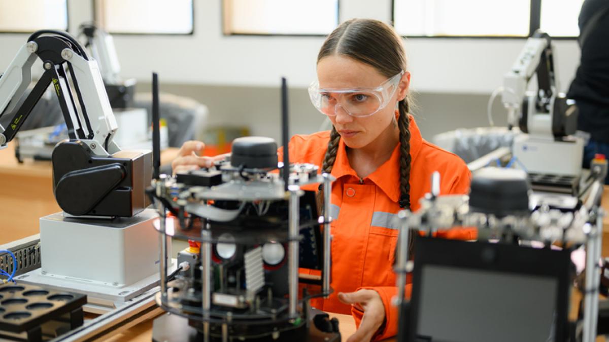 Une femme devant une machine avec des apapreils électroniques, des lunettes sur les yeux