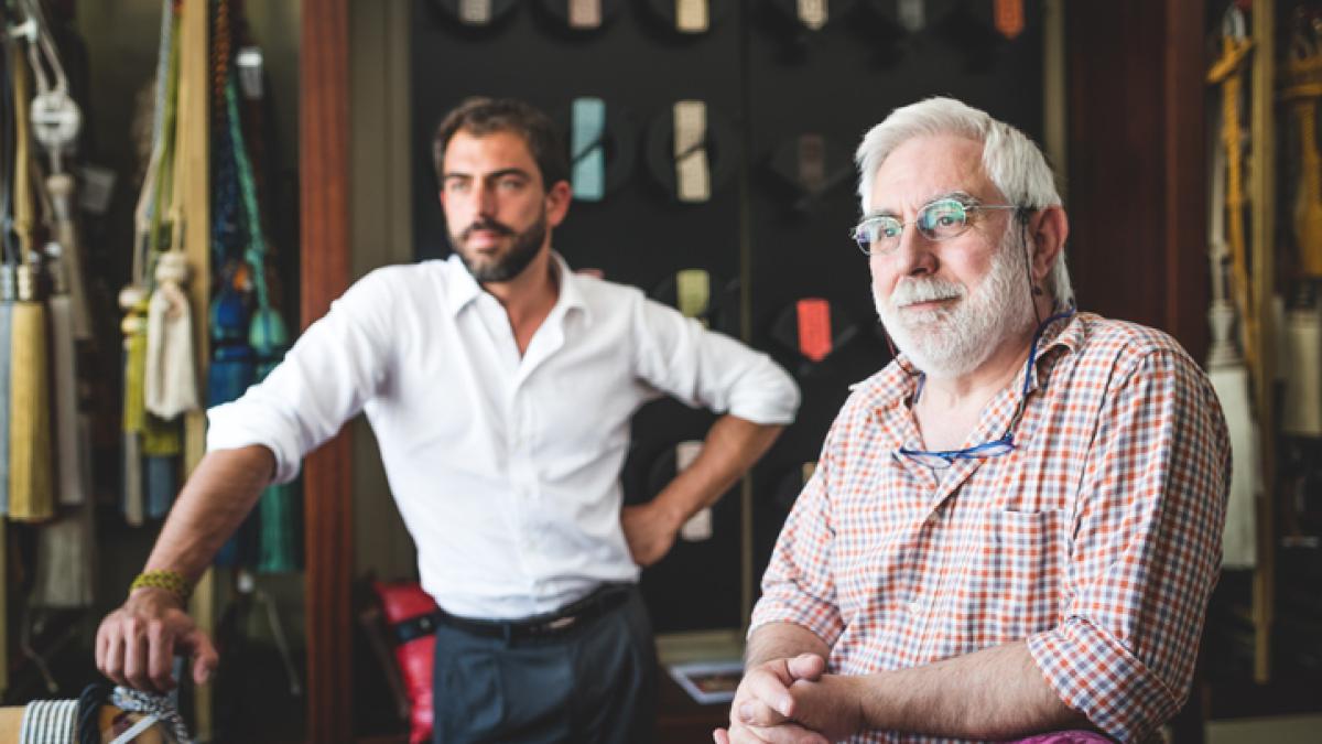 Un homme plutôt agé en premier plan regarde devant lui. Un autre homme plus jeune en arrière plan regarde dans la même direction.